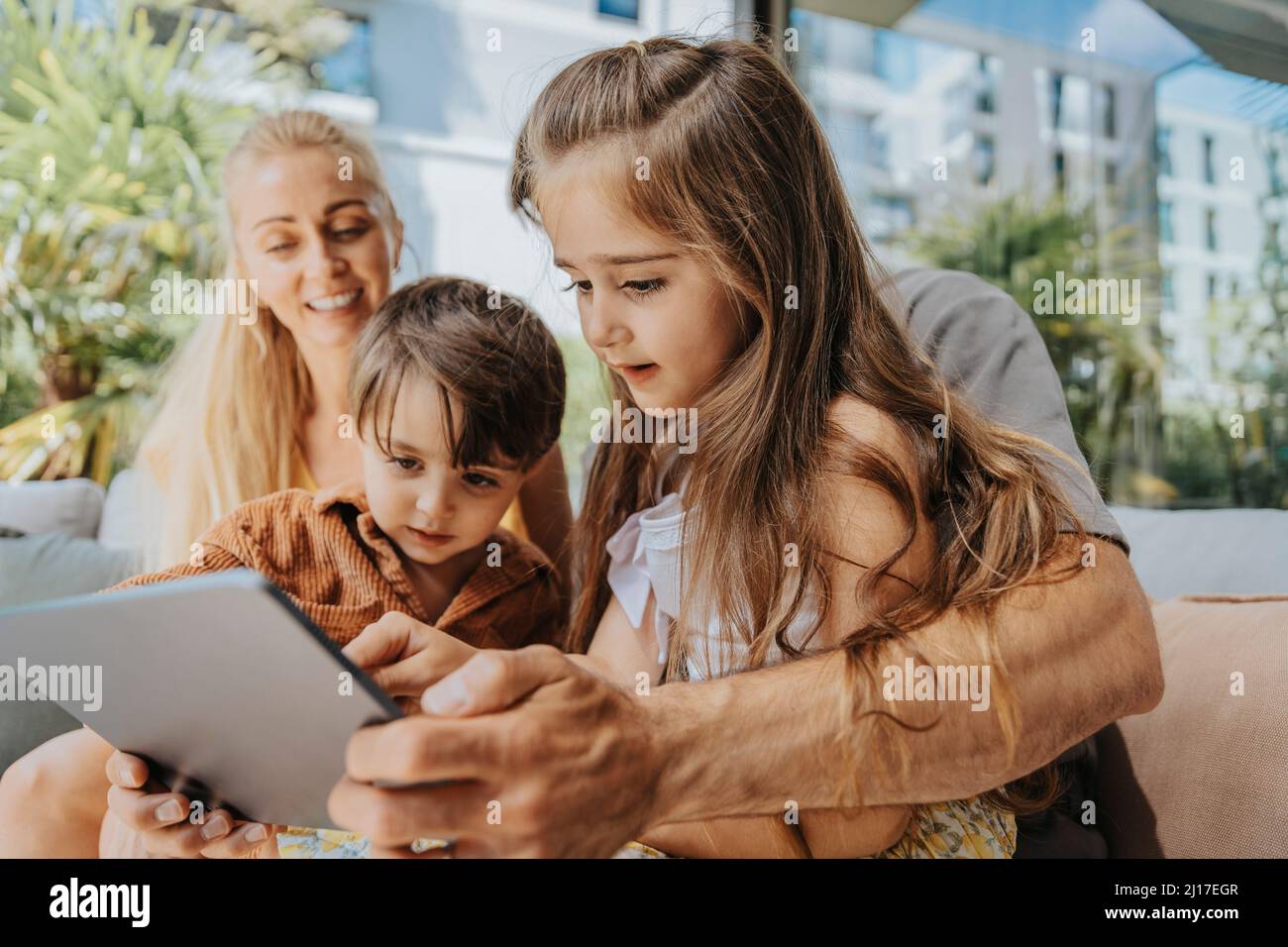 Padre e bambini che usano un tablet nel patio Foto Stock