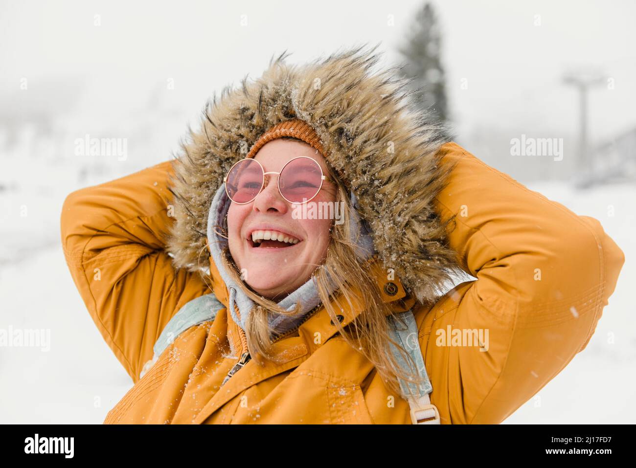 Donna felice in pelliccia giacca godendo nevicata in vacanza Foto Stock
