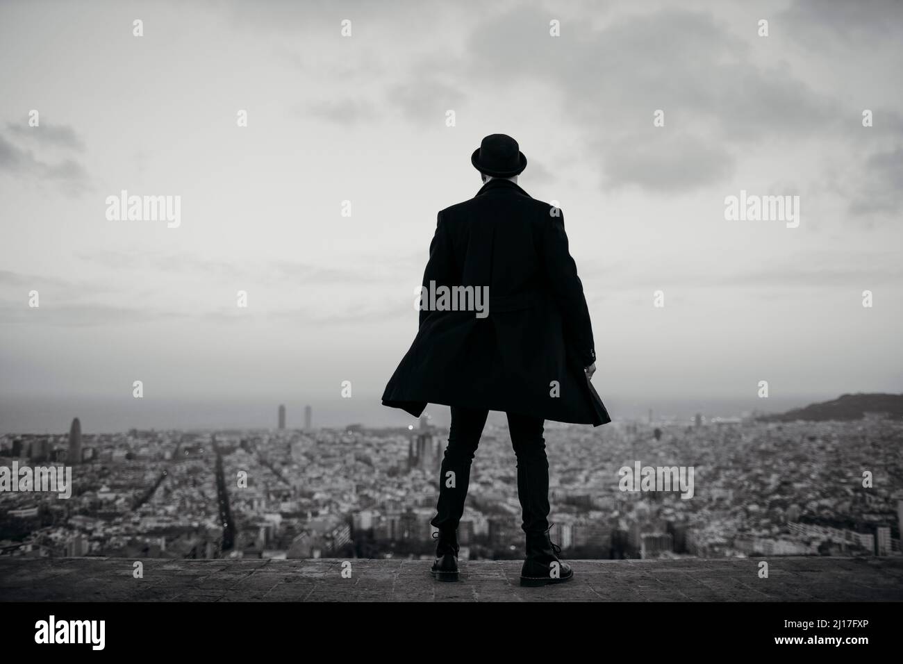 Uomo in giacca nera e cappello ammirando la città Foto Stock