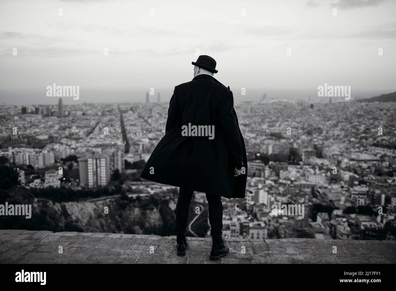 Uomo in giacca nera e cappello che guarda la città Foto Stock