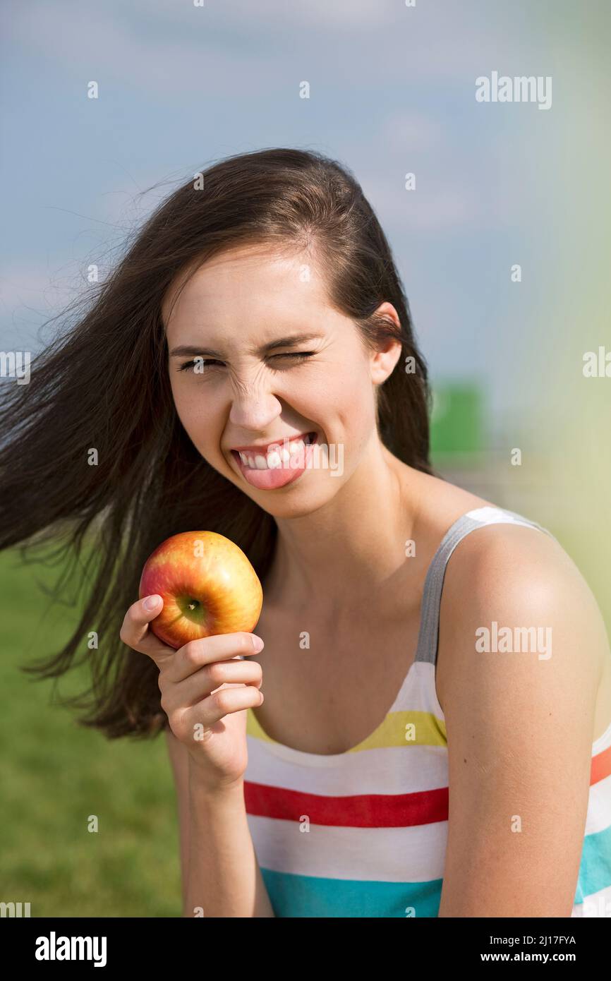 Giovane donna con l'occhio di melo che vampica e che attacca la lingua nella giornata di sole Foto Stock