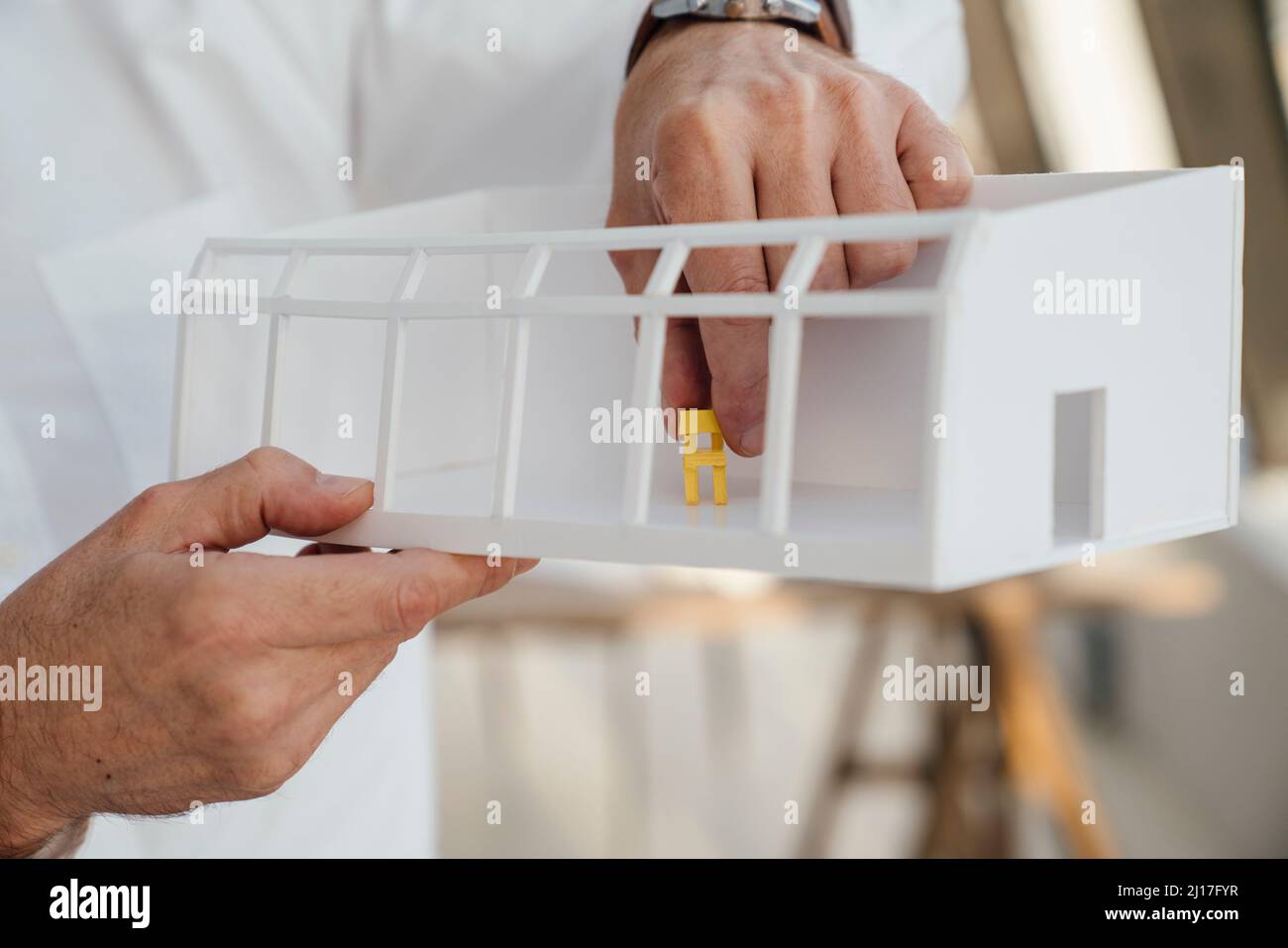 Le mani dell'uomo d'affari che tengono il modello architettonico in ufficio Foto Stock