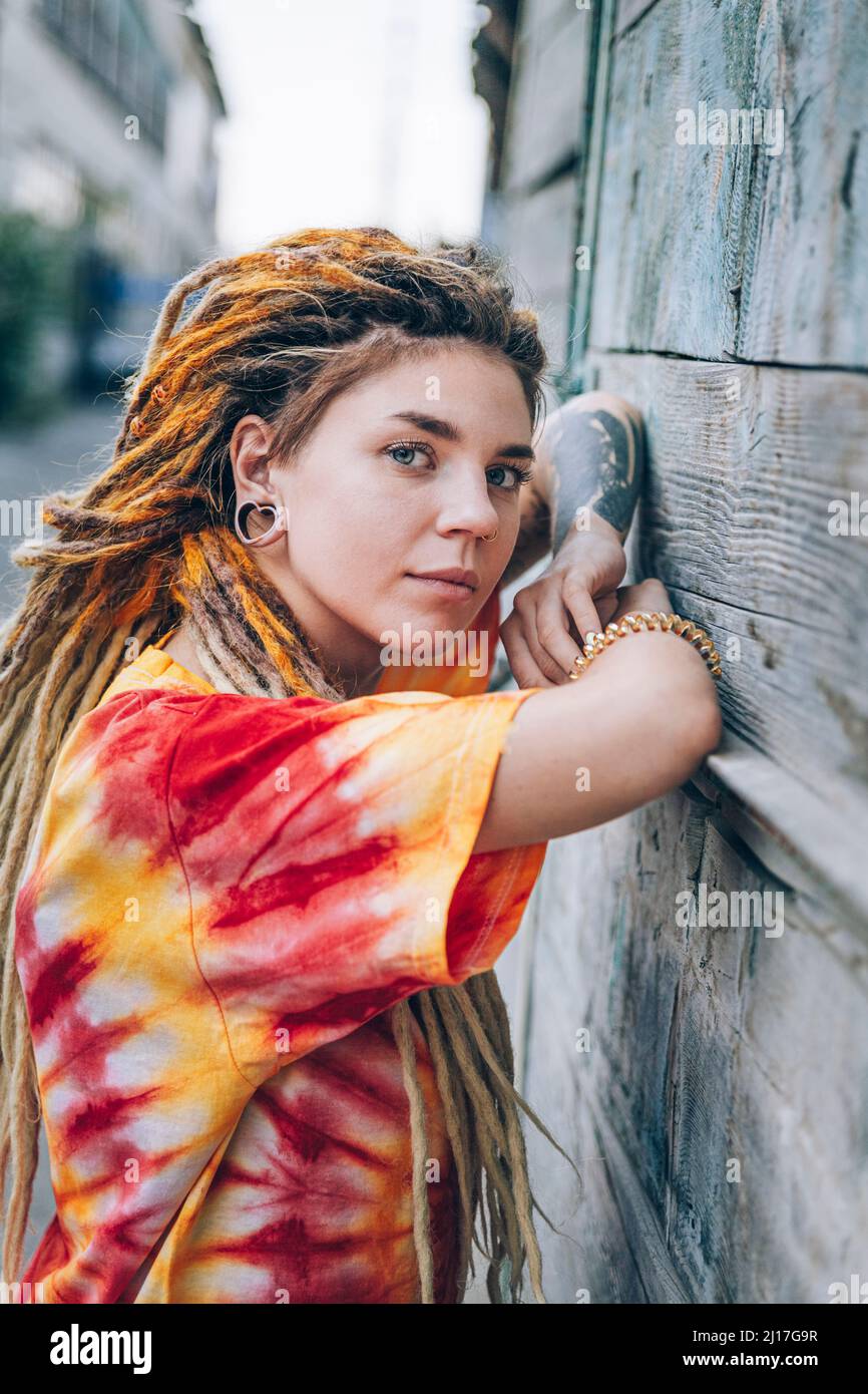 Giovane donna con dreadlock appoggiata su muro di legno Foto Stock