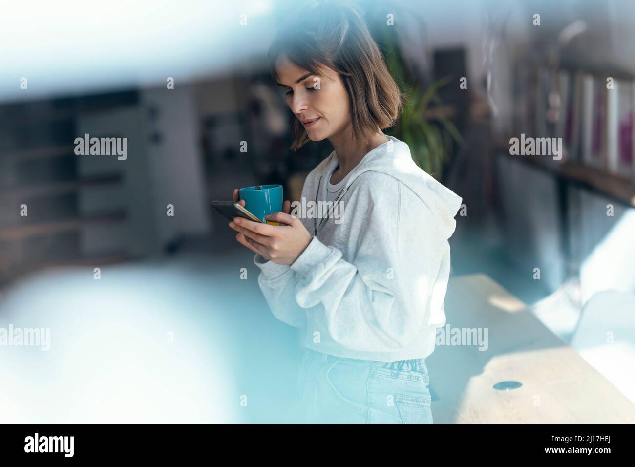 Messaggi di testo per donna su smartphone a casa Foto Stock