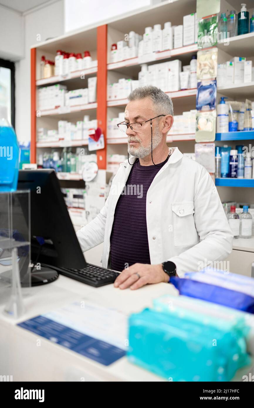 Farmacista che utilizza il computer al check-out nel negozio della farmacia Foto Stock