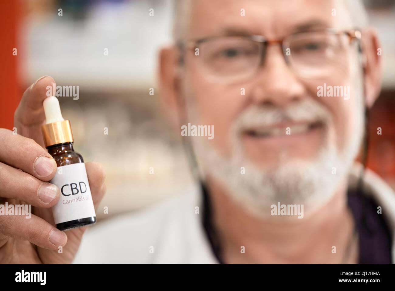 Farmacista che tiene una bottiglia di olio di cannabis in farmacia Foto Stock