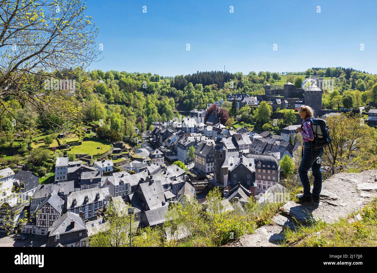 Germania, Renania settentrionale-Vestfalia, Monschau, escursionista femminile ammirando la vista della città medievale in primavera Foto Stock