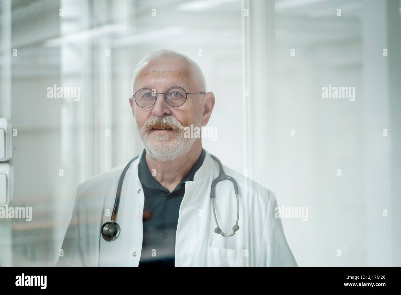 Medico senior con baffi indossare occhiali presso la clinica medica Foto Stock