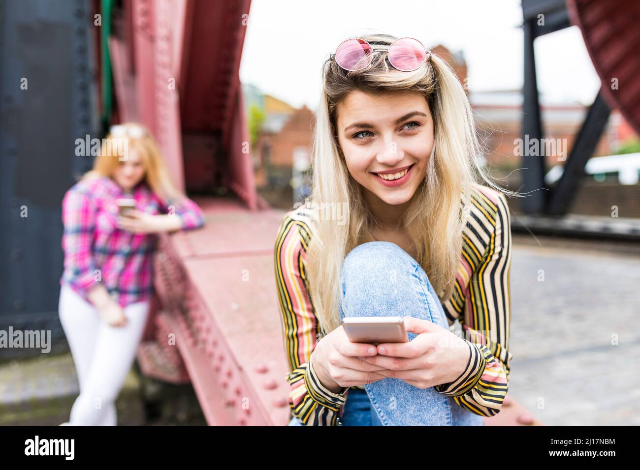 Adolescente felice che indossa occhiali da sole che reggono smartphone Foto Stock