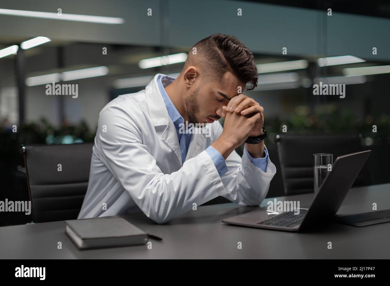 Scienziato medio-orientale stanco seduto di fronte al computer portatile Foto Stock