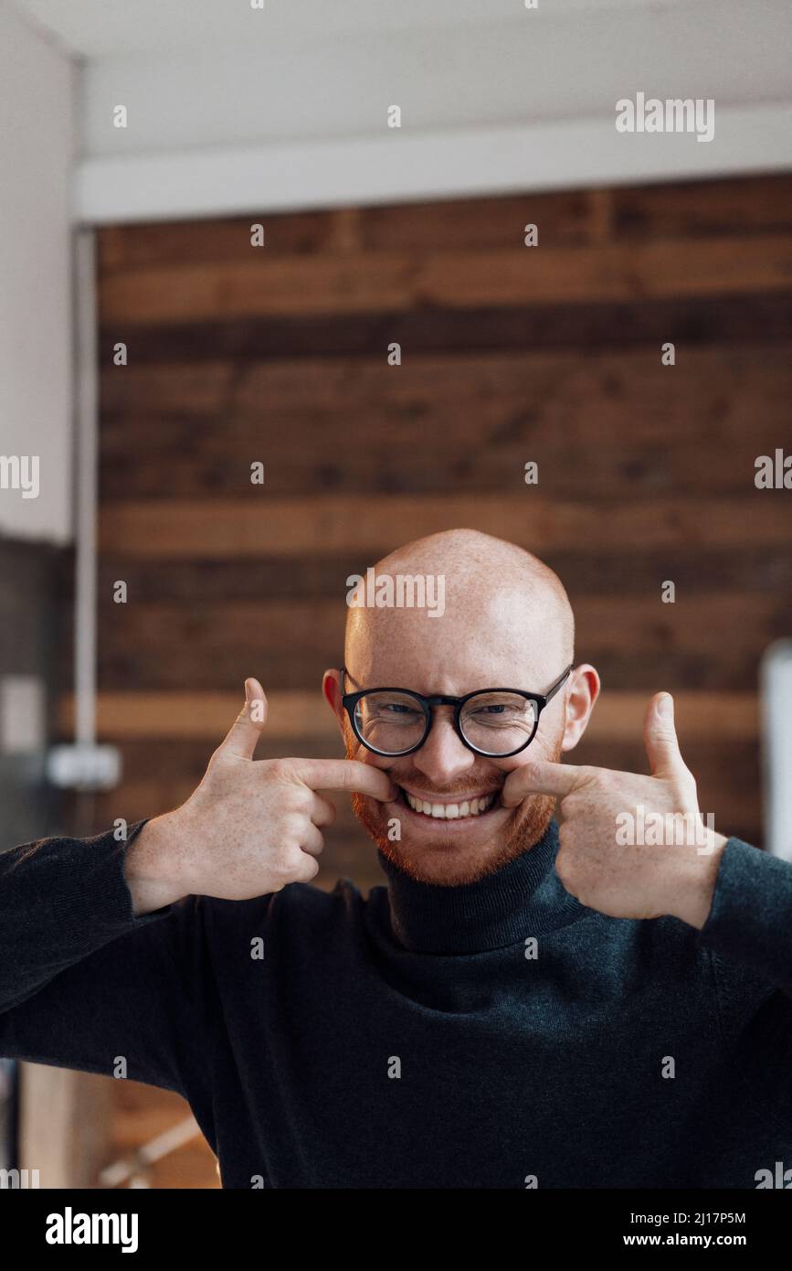 Uomo d'affari che fa faccia divertente in ufficio Foto Stock
