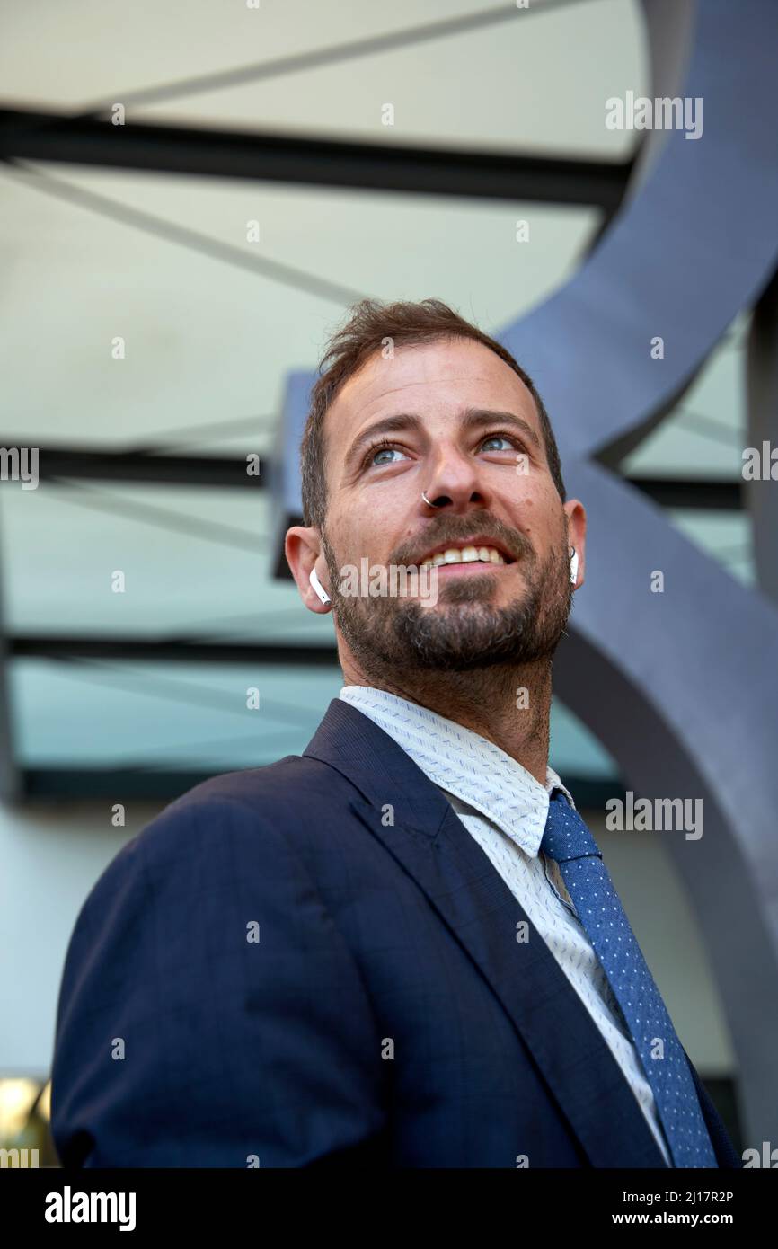 Uomo d'affari contemplativo con auricolari bluetooth Foto Stock