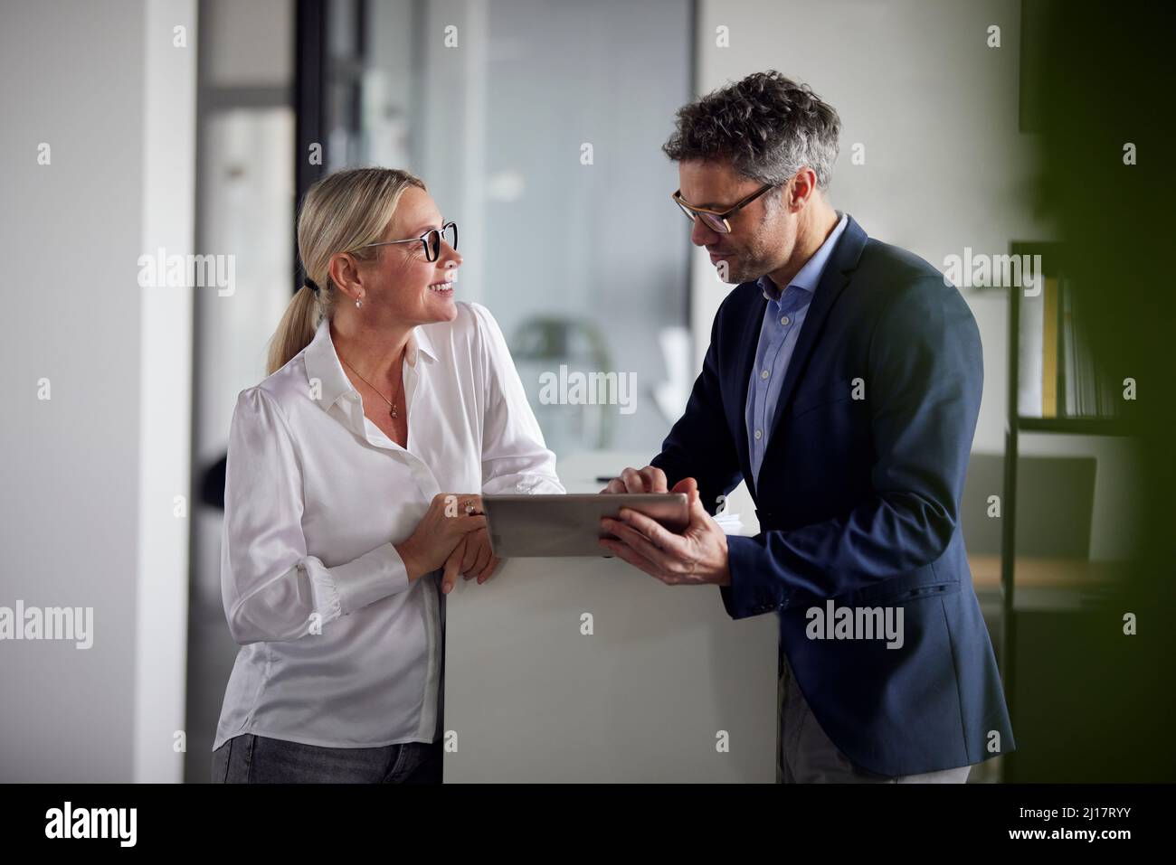 Uomo d'affari che condivide idee su un tablet PC con un collega in ufficio Foto Stock