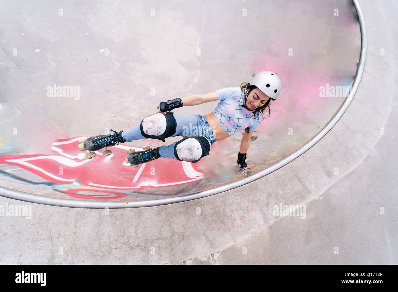 Donna che indossa il casco di pattinaggio a rotelle al parco Foto Stock