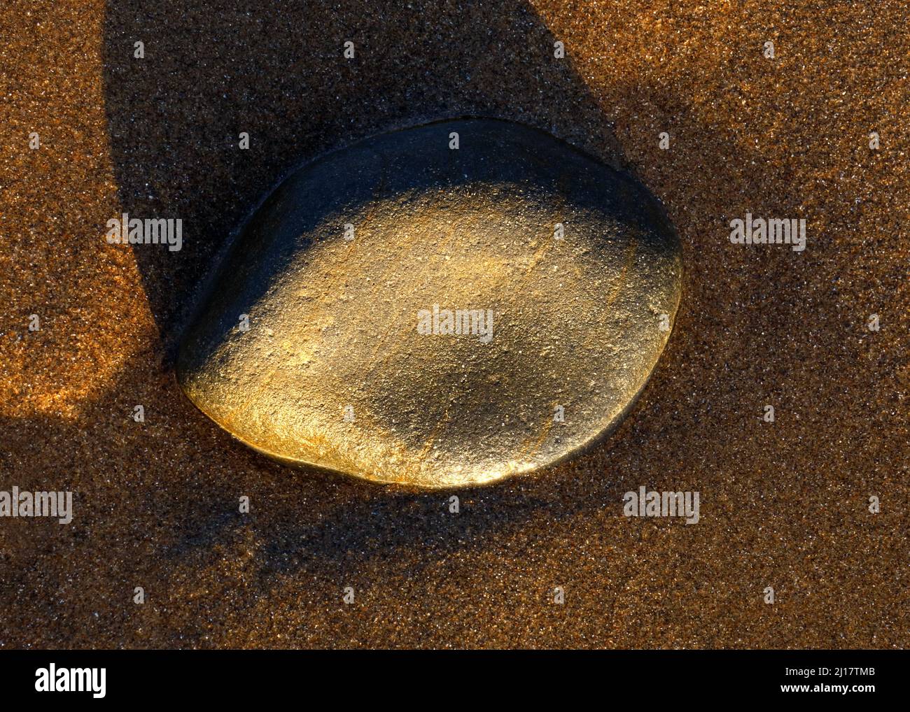 Foto a colori di pietre costiere sulla spiaggia levigata e arrotondata dai passaggi del tempo e marea contenente ciottoli di pietra con patte granuloso Foto Stock
