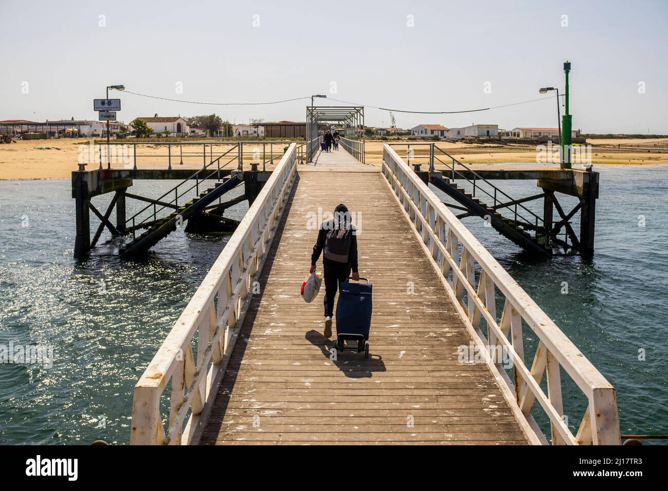 Uomo con borse sul molo di Culatra Island, Faro, Algarve, Portogallo Foto Stock