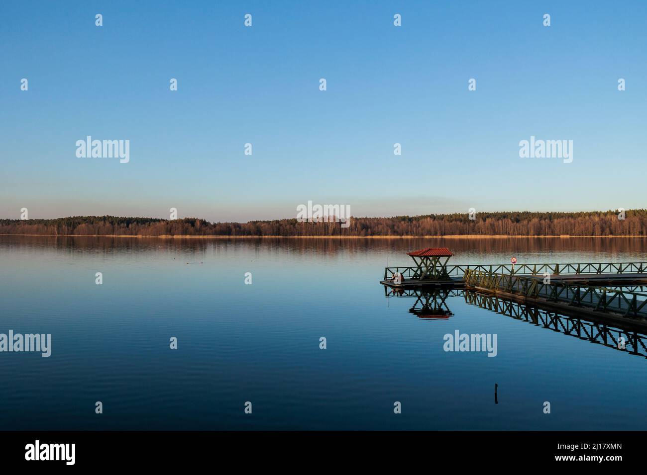 Un lago a Gołdap con due ragazze sedute su un ponte Foto Stock