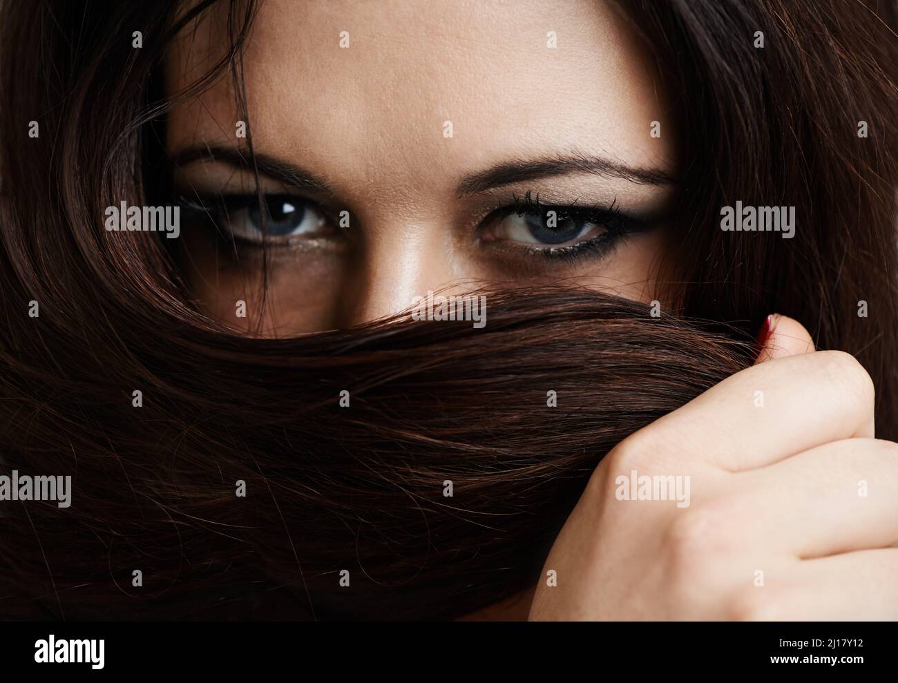 Misteriosa padrona. Ritratto corto di una bella giovane donna che copre la bocca con i capelli. Foto Stock