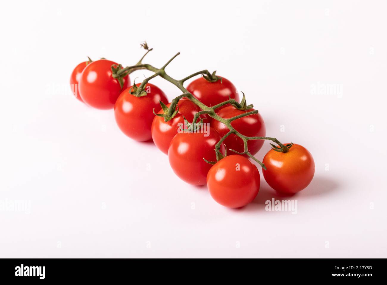 Primo piano di pomodori freschi di ciliegia rossa girati su sfondo bianco Foto Stock