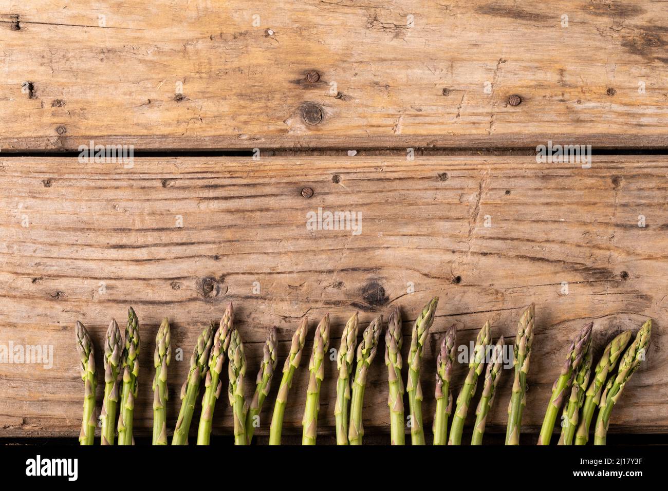 Direttamente sopra la vista di asparagi crudi disposti fianco a fianco su tavola di legno marrone Foto Stock