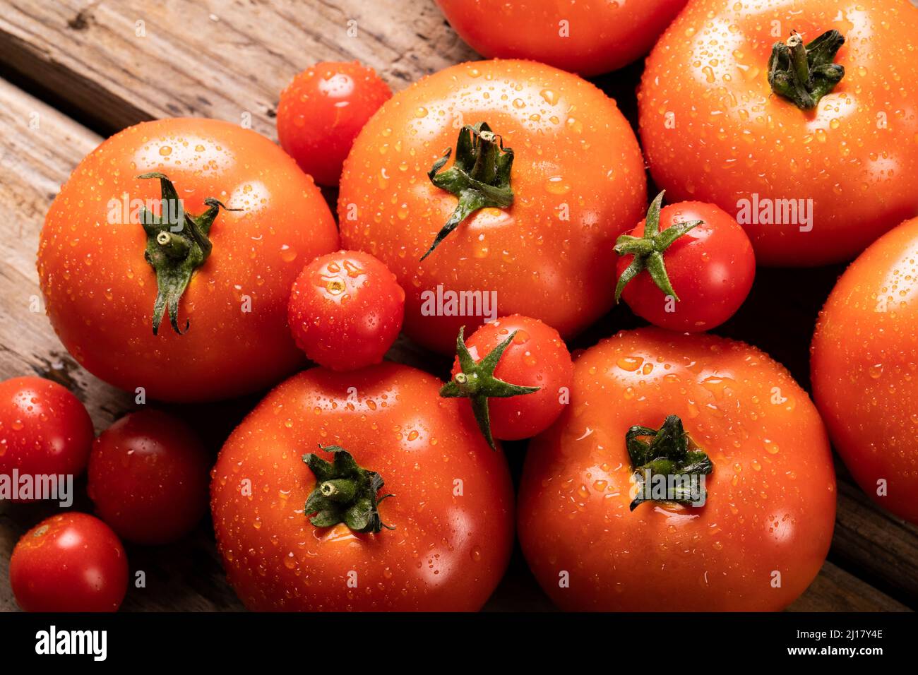 Direttamente sopra la vista dei pomodori rossi freschi con gocce d'acqua sul tavolo Foto Stock