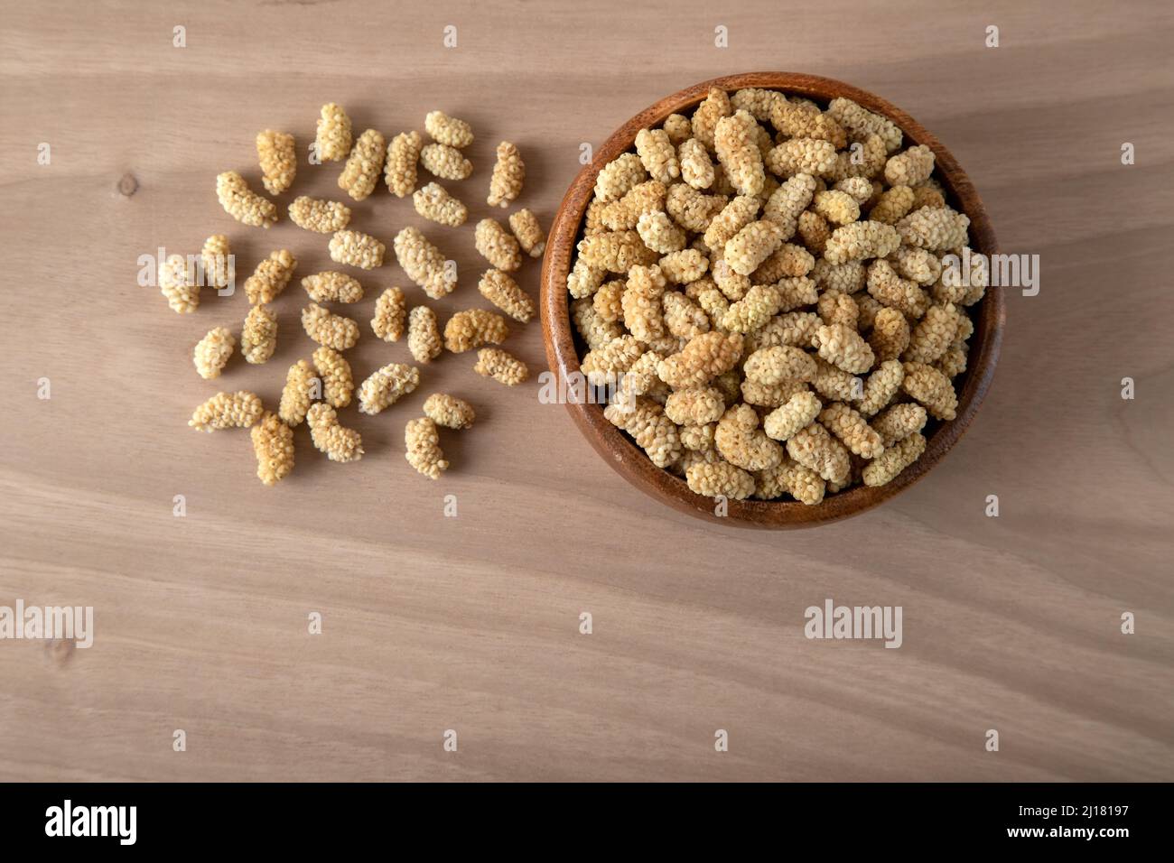 Ciotola piena di gelso secco su sfondo di legno Foto Stock
