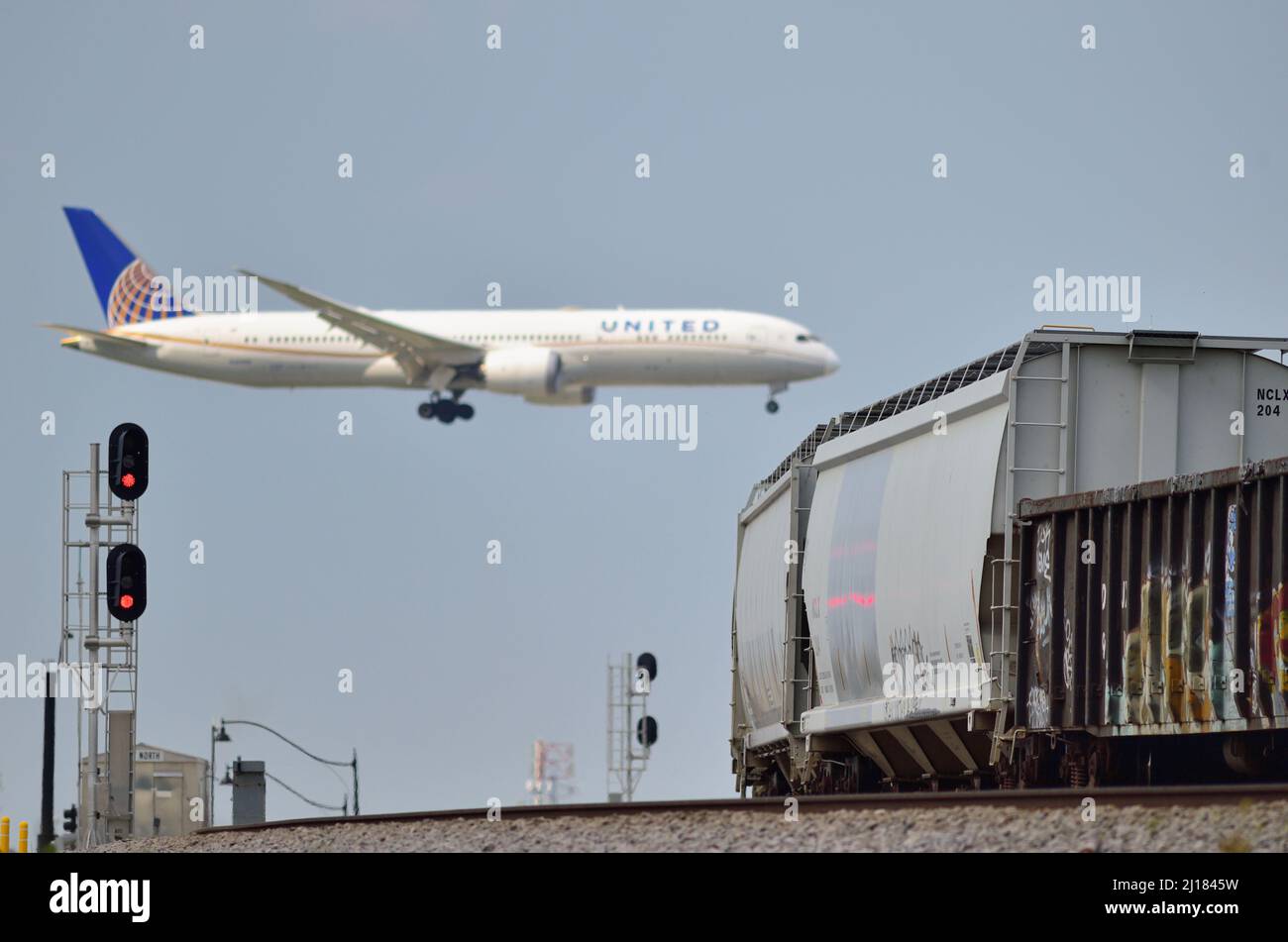 Bensenville, Illinois, Stati Uniti. Un jet si aggira sopra un treno merci mentre atterra all'Aeroporto Internazionale o'Hare di Chicago. Foto Stock