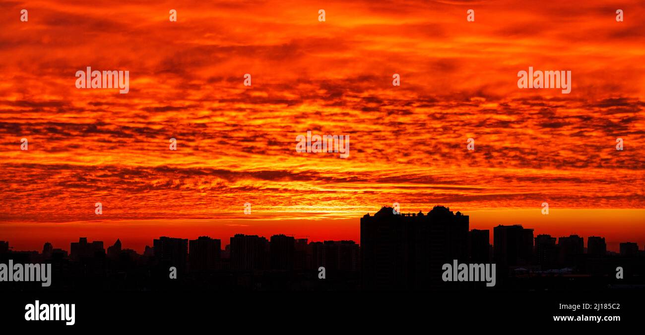 Il profilo nero della città di notte sullo sfondo di un'alba sanguinosa al mattino presto. Foto Stock