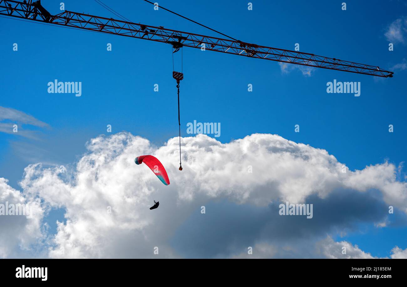 gru filigrana braccio e parapendio rosso prima del cielo blu con nuvole bianche Foto Stock