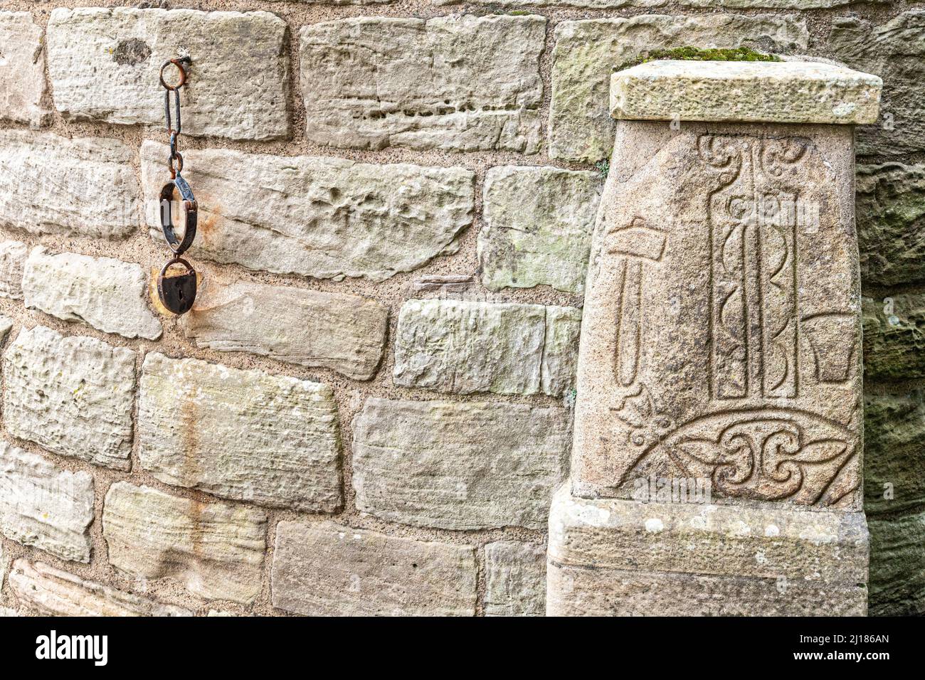 Una pietra simbolo Pictish alla base della Abernethy Round Tower, una torre in pietra di 22 metri di altezza in stile irlandese ad Abernethy, Perth e Kinross, Scozia Regno Unito Foto Stock