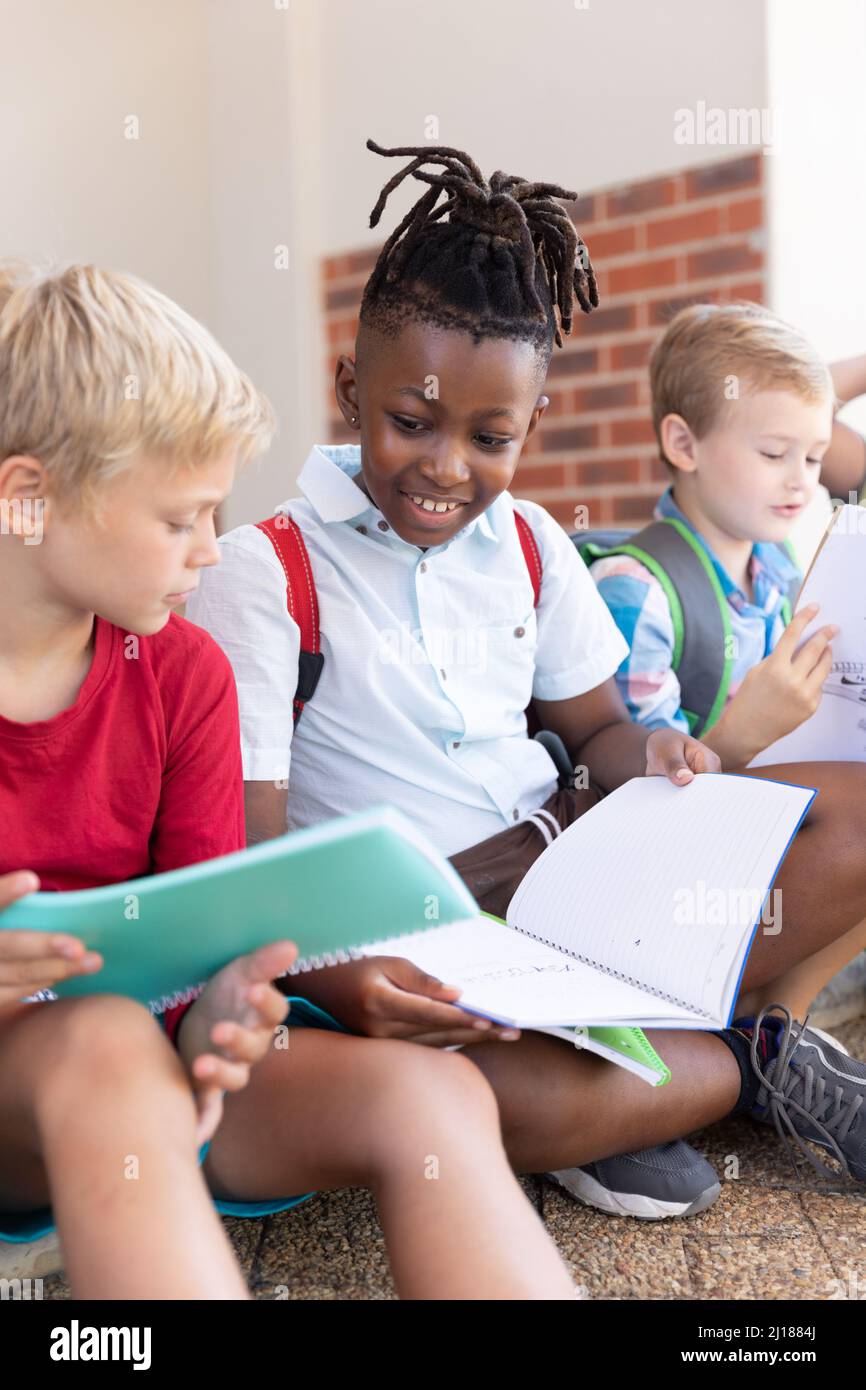 Sorridendo scolaro africano americano elementare studiare con caucasico compagno di classe a scuola Foto Stock