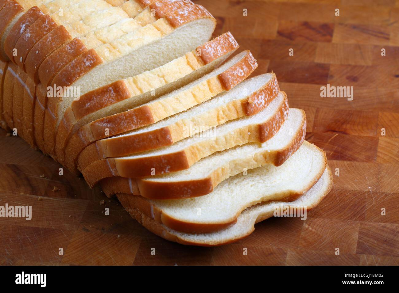 Pane bianco al latte affettato su sfondo di legno Foto Stock