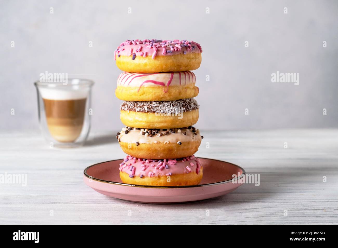 Ciambelle decorate con vetri su piatti e latte di caffè o cappuccino Foto Stock