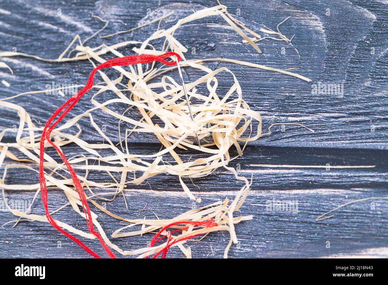 La foto mostra un ago con filo rosso con lana di legno Foto Stock