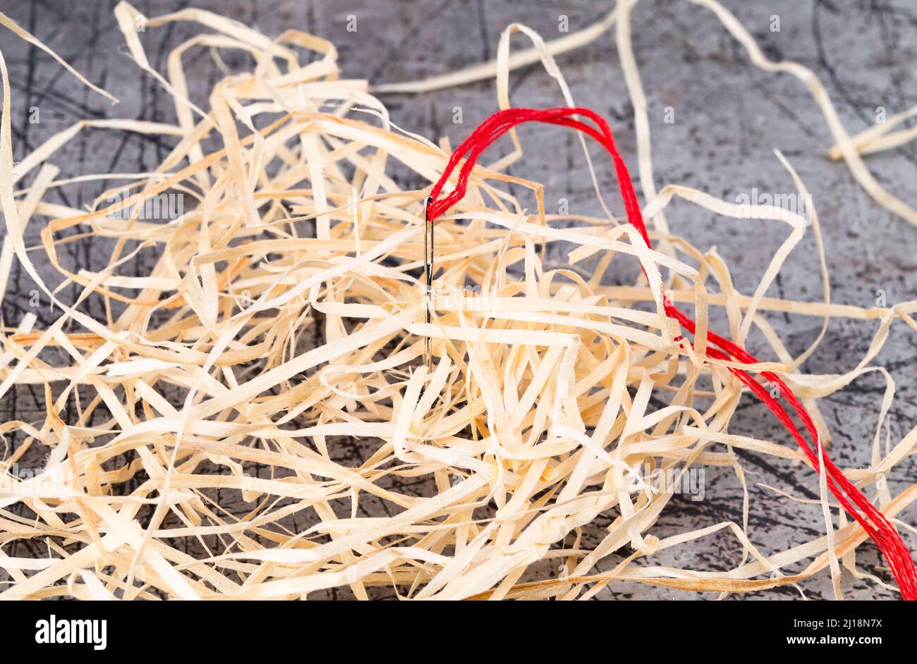 La foto mostra un ago con filo rosso con lana di legno Foto Stock