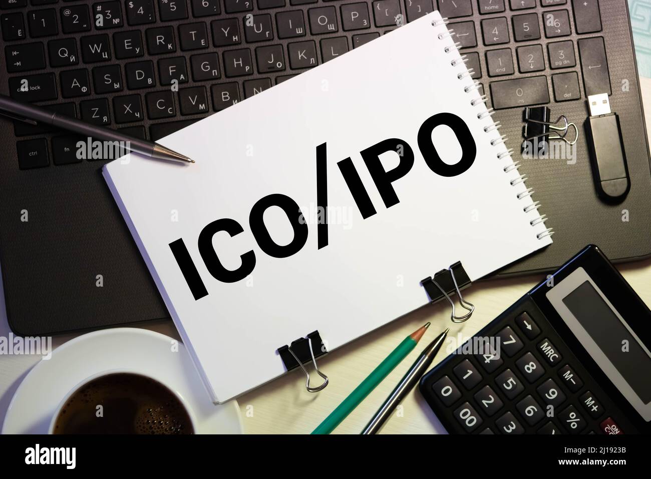 Un notebook con note di Business iniziale offerta di moneta ICO vs IPO Offerta pubblica iniziale con gli strumenti di office giallo su sfondo blu. Concetto di ch Foto Stock