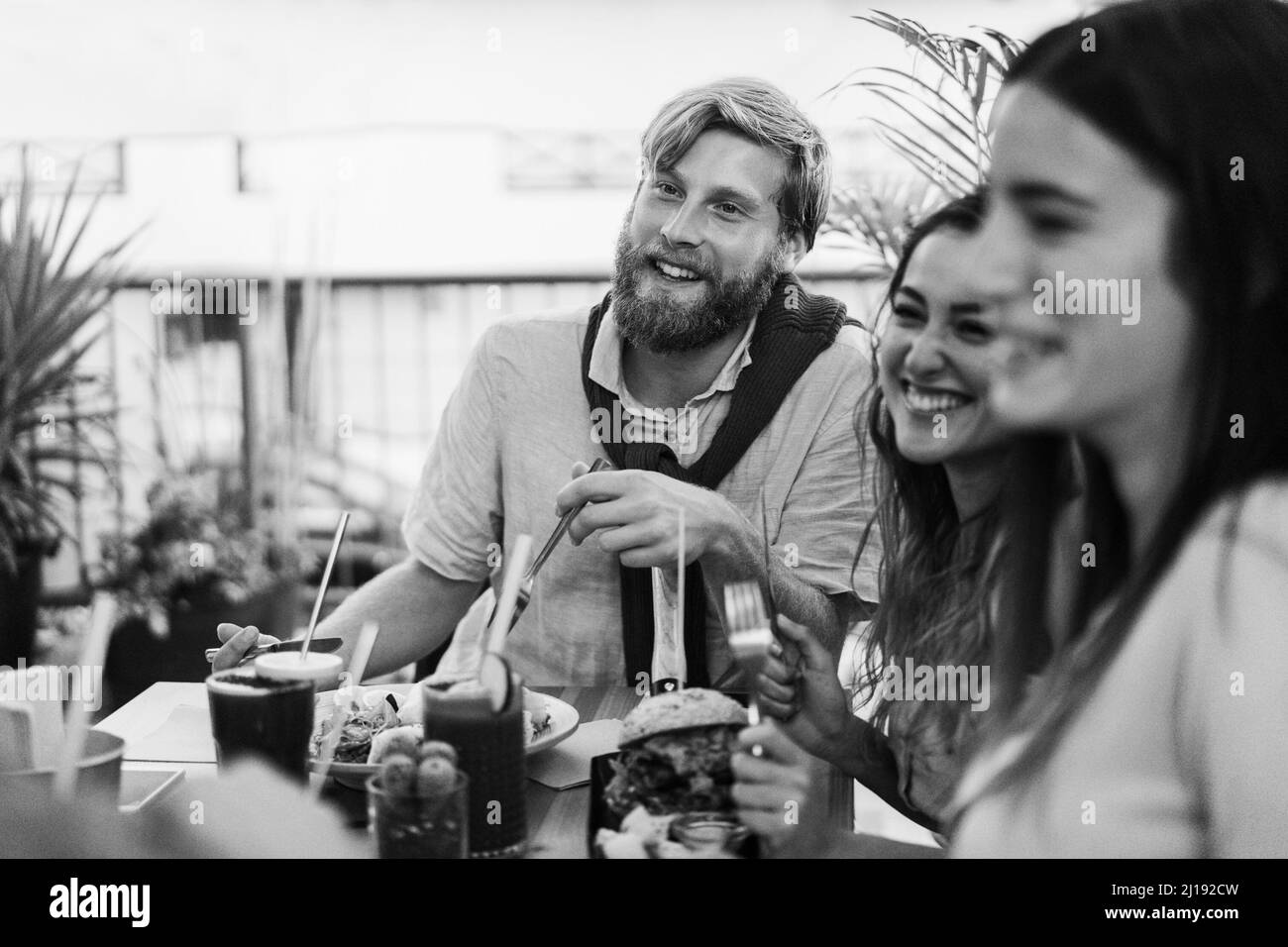 I giovani mangiano il brunch e bevono frullati al ristorante del bar di cibo sano - Focus on man face - edizione in bianco e nero Foto Stock