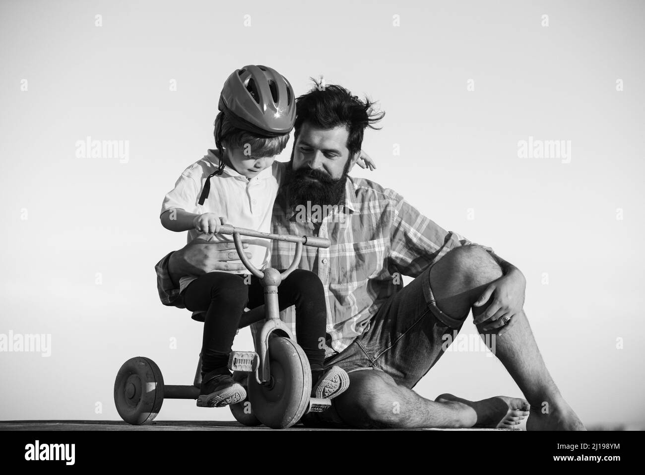 Padre insegnando figlio bici a cavallo. Felice papà che aiuta il figlio eccitato a cavalcare una bicicletta. Fiducia e supporto. Sensazione di sostegno da parte del genitore, parentale. Padri Foto Stock