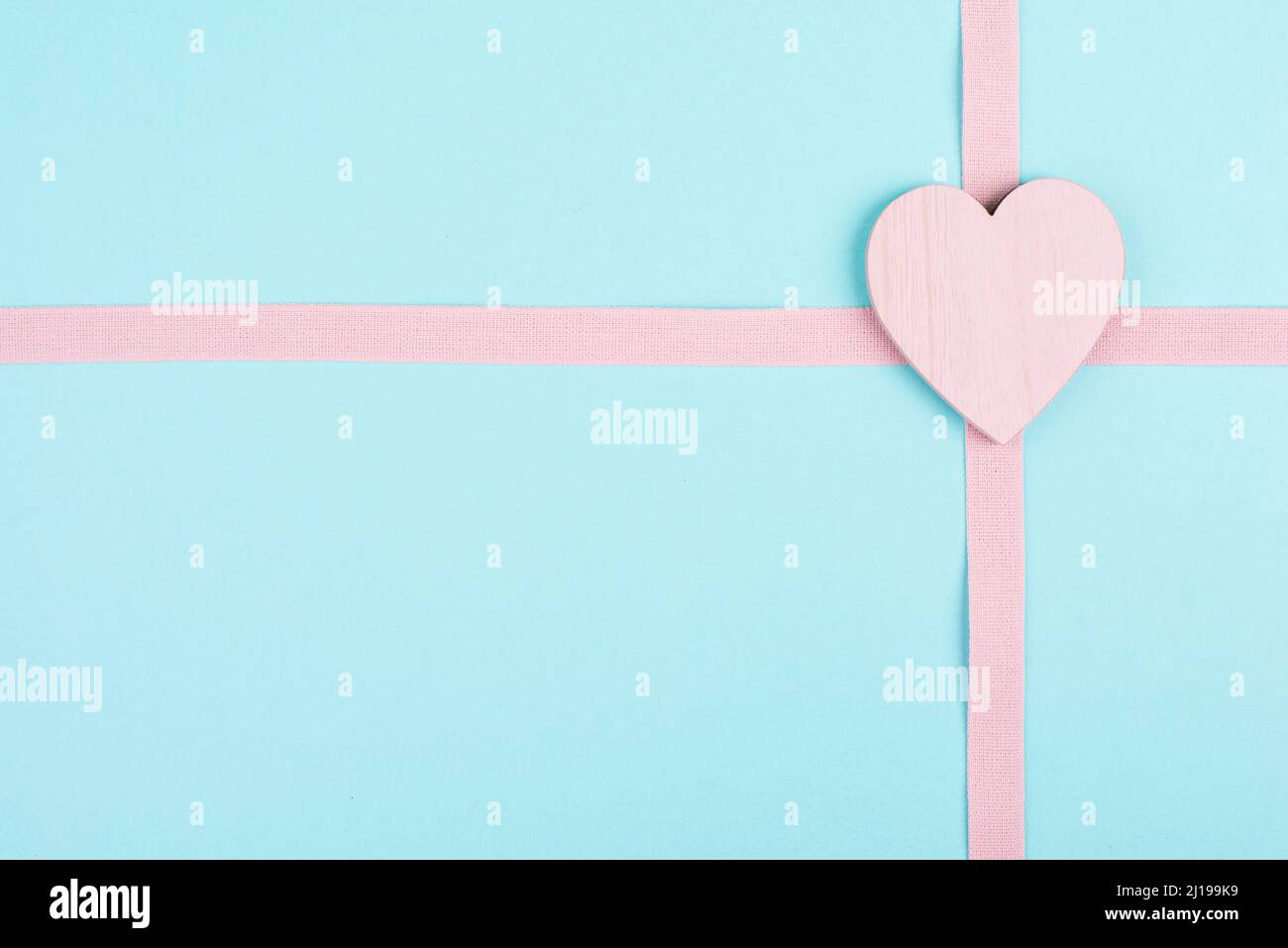 Cuore di legno su sfondo rosa e azzurro, sfondo di vacanza, giorno di San Valentino, amicizia, amore e simbolo di carità, scatola regalo Foto Stock
