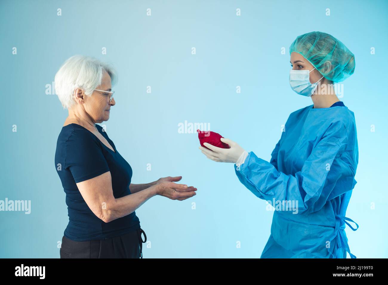 Importanza metaforica della salute. Cardiologo che dà il cuore artificiale alla nonna caucasica anziana con malattia cardiovascolare. Foto di alta qualità Foto Stock