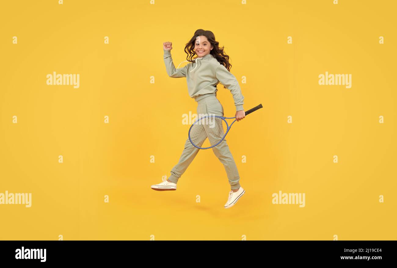 felice energica ragazza teen salto in abbigliamento sportivo con badminton racchetta in esecuzione al successo, sbrigati. Foto Stock