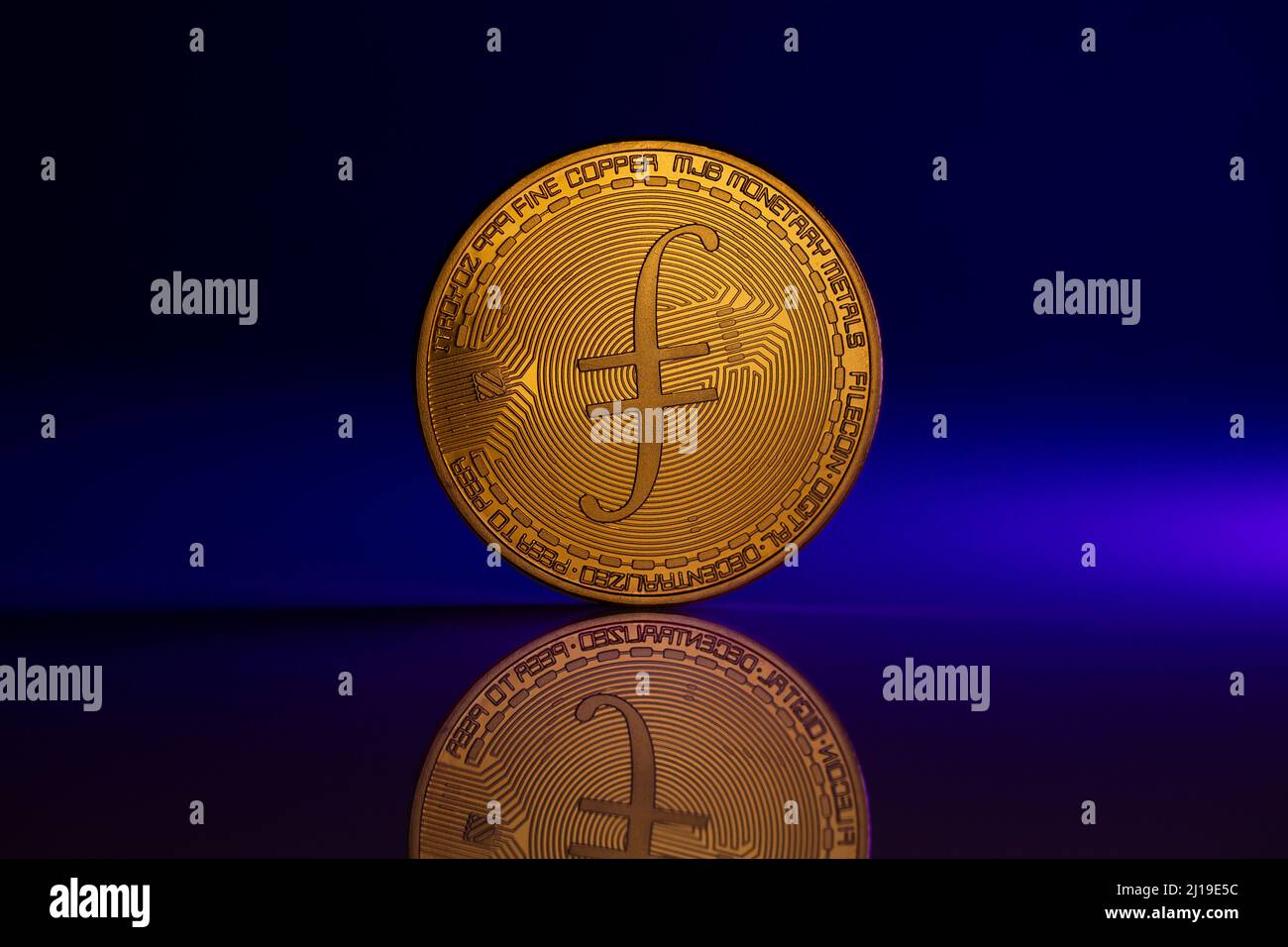 Filecoin fil Coin fisico posto su superficie riflettente e illuminato con luce blu Foto Stock