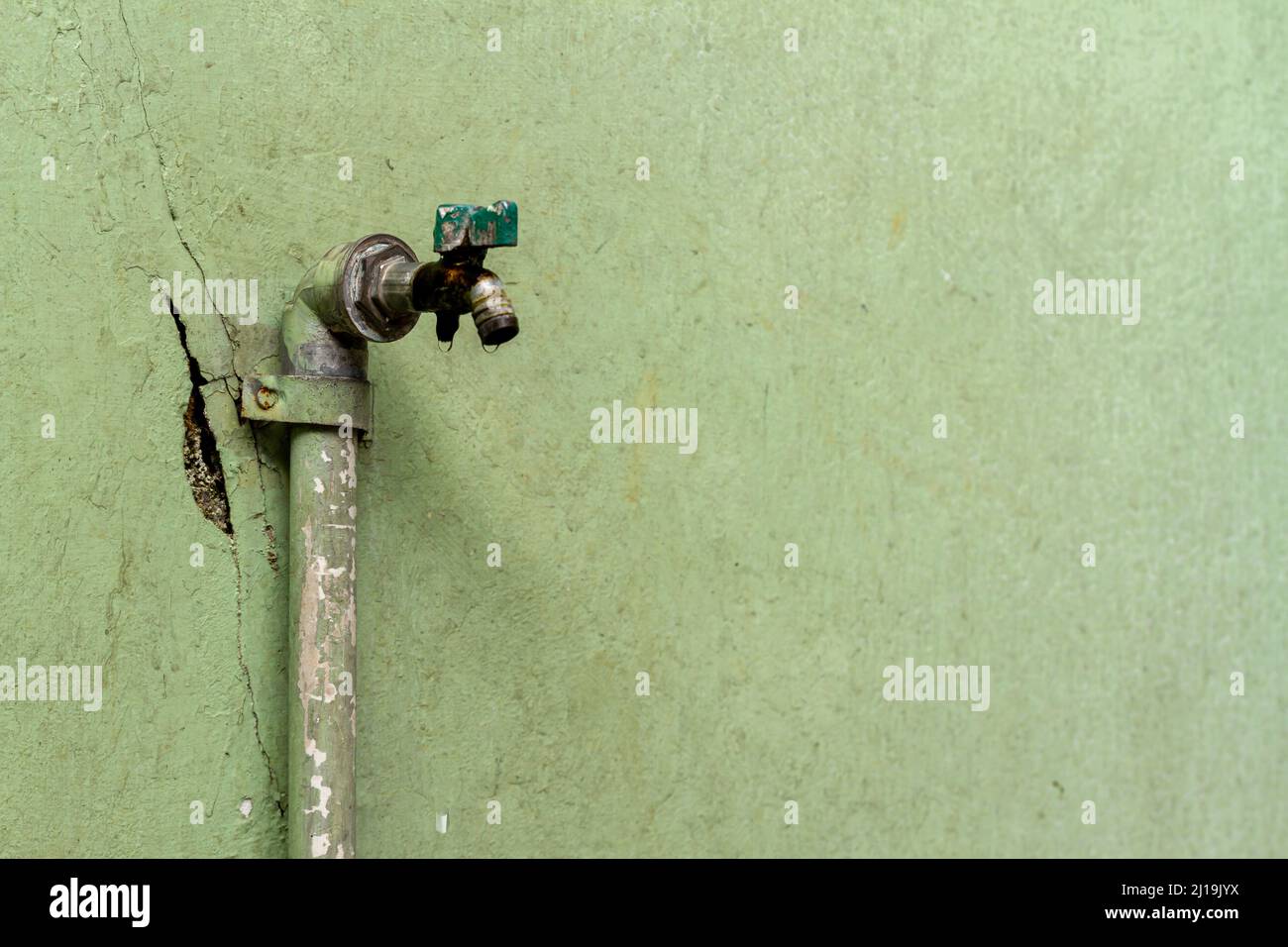 Un rubinetto d'acqua vecchio e non trattato ha una perdita intorno al buco, facendo aumentare il consumo di acqua pulita e sprecato, il concetto di risorse naturali contro Foto Stock