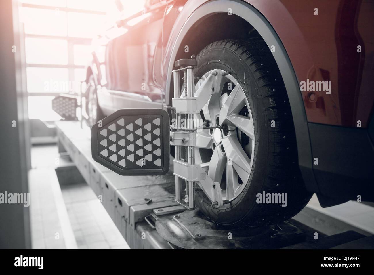 Veicolo interno officina garage per lavori di fissaggio campanatura auto. Eseguire il primo piano dell'allineamento delle ruote del veicolo sul supporto con il controllo dei sensori nella stazione di servizio. Foto Stock