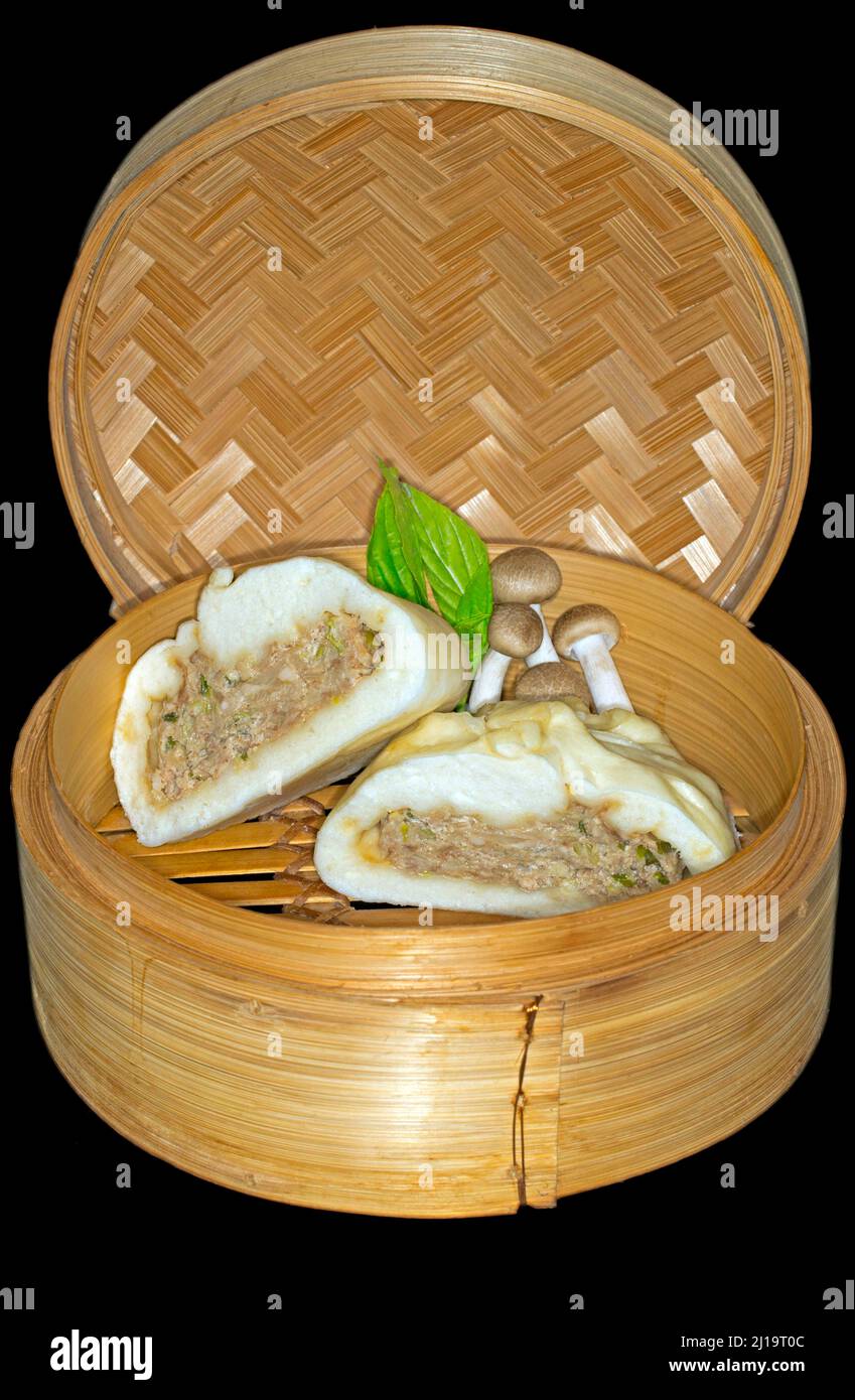 Bhan bao dimezzato farcito con carne di maiale e funghi shimeji, adagiato in un cestino di bambù Foto Stock