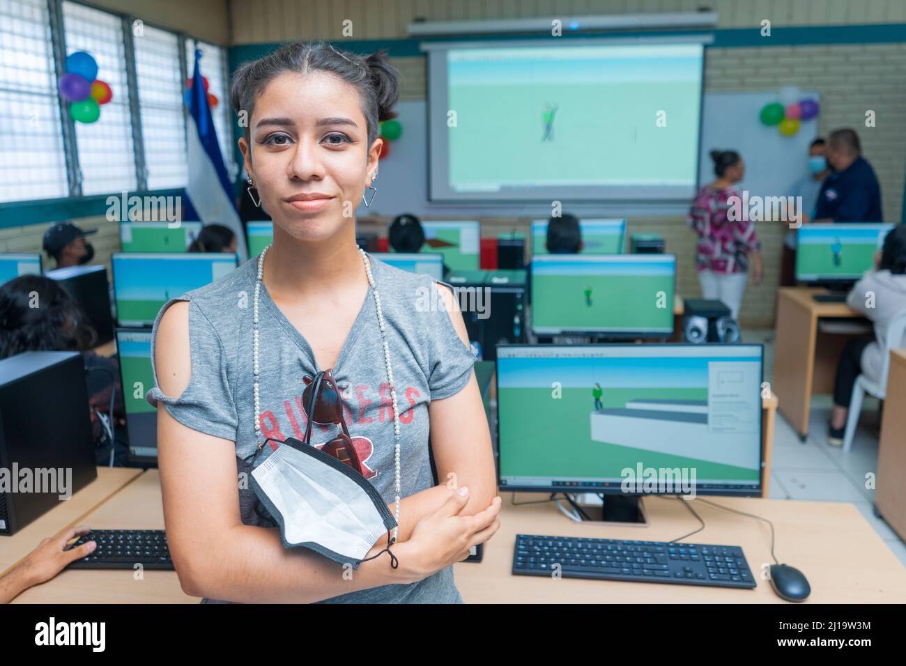 Ritratto di mezza lunghezza di una giovane donna latina dell'America Centrale in una classe piena di computer Foto Stock