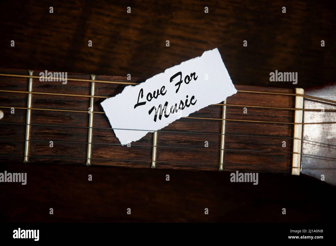 Amore per il testo musicale su carta strappata con sfondo chitarra. Concetto di musica Foto Stock