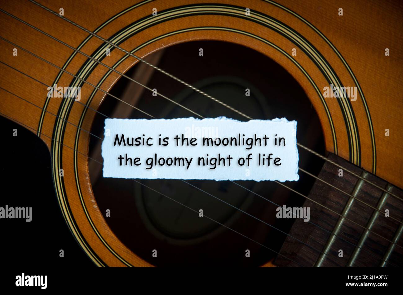 Testo di citazione motivazionale su carta bianca strappata - la musica è il chiaro di luna nella notte cupa della vita. Con sfondo di chitarra. Foto Stock