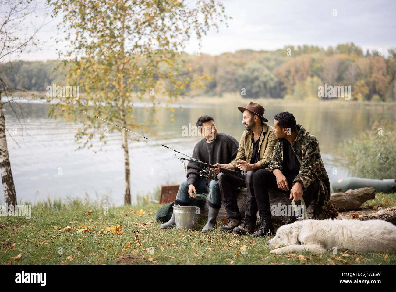 Gli amici maschi multirazziali riposano e parlano in natura Foto Stock