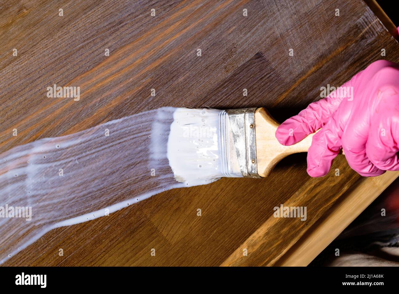 vernici a mano gloved con spazzola un asse di mobilia del pino colorato in casa Foto Stock